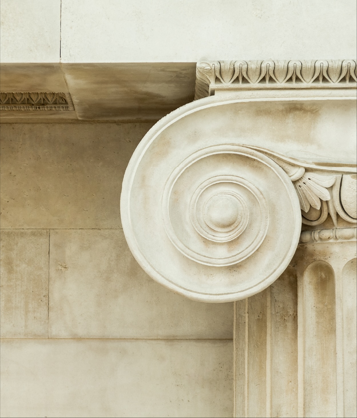 Close up of a spiral pattern at the top of a Roman-style stone column.